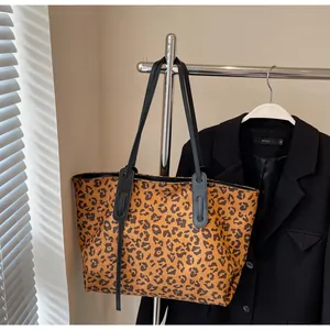 Close-up of leopard print tote bag hanging on a rack beside a black blazer jacket