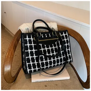 Detail of black and white tweed tote bag with gold zipper pocket and leather handles