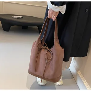 Detail of a brown suede tote bag with a decorative bow and smooth leather stitching