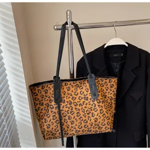 Macro detail of the leopard print fabric texture and black faux leather strap of tote bag