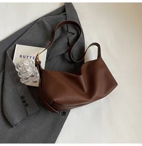 Détail du sac à bandoulière en cuir marron foncé au design minimaliste en demi-lune