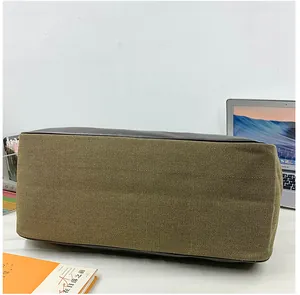 Detail of the brown canvas travel bag with dark leather edges on a white desk