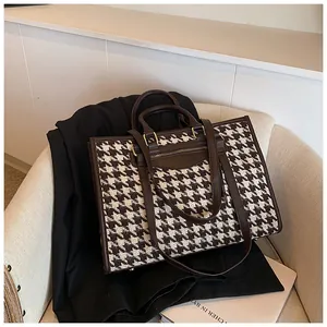Detailed view of houndstooth tote bag on a beige sofa with elegant leather straps