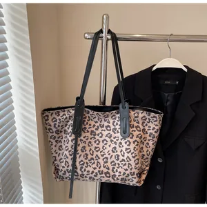 Detail view of leopard print tote bag hanging next to a black blazer in natural light