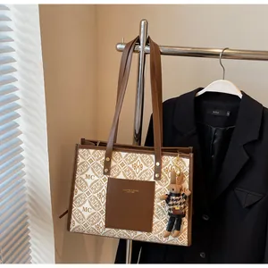 Detail of vintage tote bag with MC pattern and leather straps hanging on a metal hook