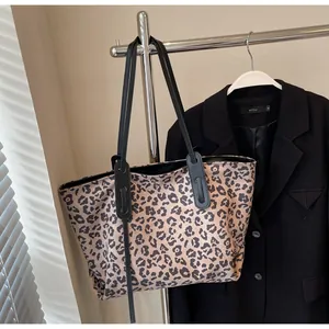 Detailed view of the leopard print tote bag with black leather shoulder straps on a hanger
