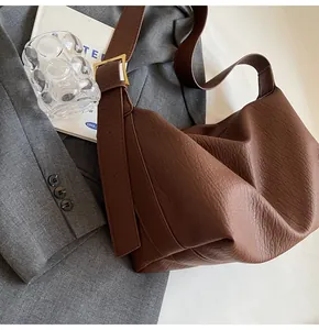 Détail du sac en cuir marron à motif litchi avec boucle en métal doré sur un blazer