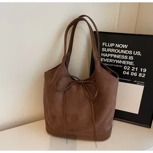 Detailed texture of brown suede tote bag with leather piping and thin bow design