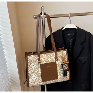 Detail of a patterned tote bag with a leather pocket and cute rabbit doll keychain
