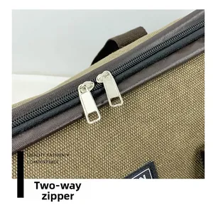 Detail view of the two-way metal zipper on a large canvas travel bag with leather trim