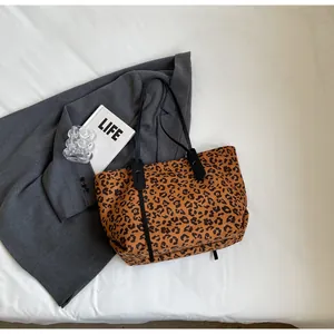 Macro shot of large leopard print tote bag flat lay on white fabric with accessories