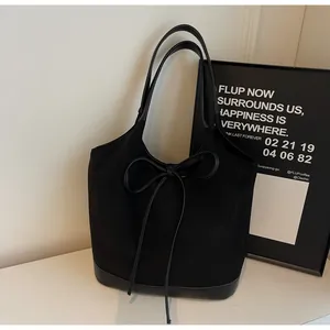 Close-up of black suede tote bag with leather拼接, featuring a large bow detail