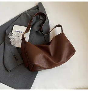 Détail de la texture cuir grainé marron foncé et boucle dorée sur un blazer gris chic