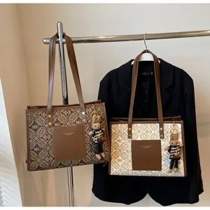 Detail of trendy tote bags with monogram pattern and cute plush rabbit charms for commute