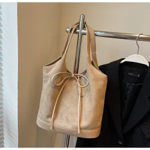 Detail of apricot tote bag with bow drawstring and matte suede splicing on office suit