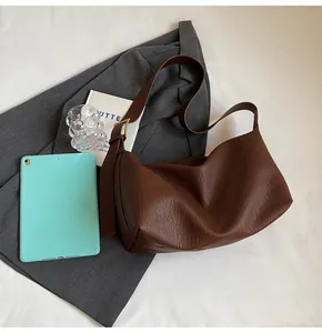 Détail du sac à main en cuir marron grainé avec boucle dorée et large bandoulière souple