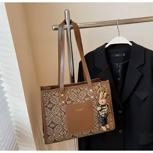 Close-up of vintage brown tote bag with classic logo pattern and cute rabbit charm