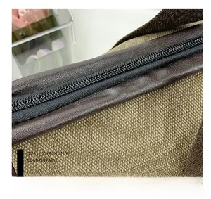 Detailed macro view of the smooth black zipper on khaki canvas with leather trim