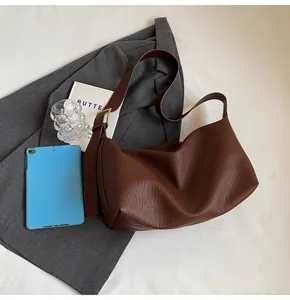 Détail du cuir marron foncé et boucle dorée sur un sac à bandoulière chic de style hobo