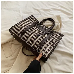 Detail of houndstooth tote bag featuring brown leather trim and metallic rivet accents