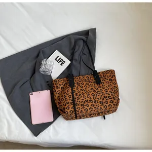 Close-up of leopard print tote bag with black leather straps on a white background