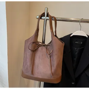 Detail of dark brown matte tote bag with bow tie and smooth leather stitching