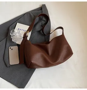 Détail de la texture cuir marron souple et boucle dorée sur un sac cabas élégant