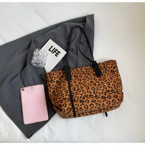 Detailed view of leopard print tote bag with black leather straps and premium finish