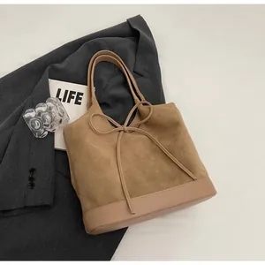 Detail of a brown suede tote bag with leather拼接, bow ornament and large capacity