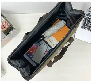 Top view of spacious canvas travel bag interior showing laptop and daily essentials