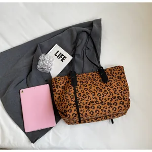 Detail shot of leopard print tote bag on white bedsheet with lifestyle accessories