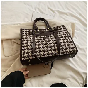 Large houndstooth tote bag shown next to a smartphone to demonstrate its spacious capacity
