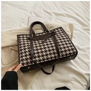 Macro view of brown houndstooth tote bag featuring gold hardware and leather details