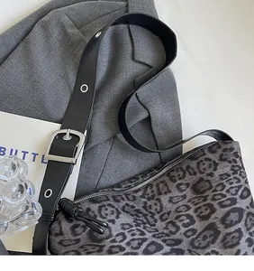 Détail du sac bandoulière à motif léopard avec bandoulière en cuir noir et boucle argentée