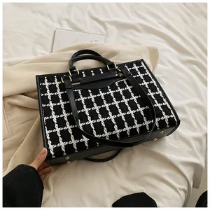 Close-up of black and white tweed tote bag showing fabric texture and gold rivets
