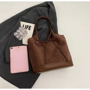 Detailed macro view of dark brown suede tote bag with leather bow and flat bottom base