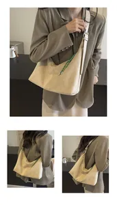 Détail d'un grand sac hobo en daim beige avec un cordon de serrage tressé vert et blanc