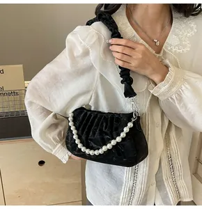 Detail of black pleated shoulder bag with elegant pearl strap and fabric strap