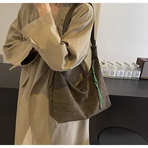 Détail du sac fourre-tout en daim marron foncé avec tirette verte tressée et coutures