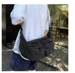 Detail of a black nylon crossbody bag with functional zippered pockets and drawstring