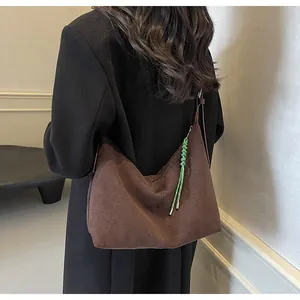 Détail du sac hobo en daim marron café avec un ornement tressé vert contrastant