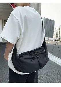 Detailed side view of black nylon messenger bag with multiple zipper pockets and drawstrings