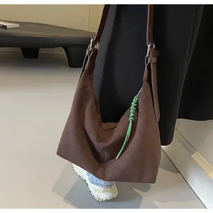 Détail d'un cabas en daim marron foncé avec un accessoire en corde tressée verte