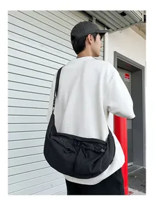 Rear view of a black nylon crossbody bag featuring double pockets and drawstring details