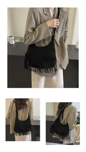Detail van zwarte suède hobo tas met lange franjes en geknoopte schouderband