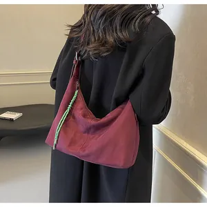 Détail macro du sac hobo en daim bordeaux avec un cordon décoratif tressé vert