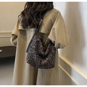 Sac à bandoulière chic imprimé léopard gris foncé avec sangle noire sur un trench-coat