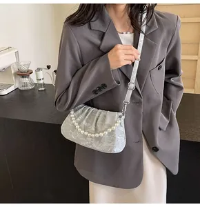 Detail of silver pleated bag featuring pearl chain and adjustable branded shoulder strap