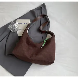 Gros plan du sac cabas en daim marron foncé avec bandoulière cuir et charme tressé