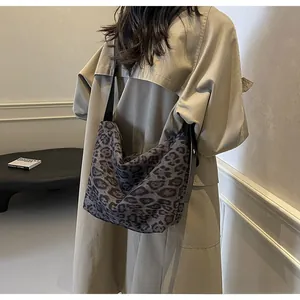 Sac hobo à motif léopard avec bandoulière large porté par un mannequin en trench-coat
